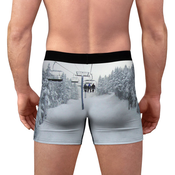 a man wearing a pair of boxer shorts with a ski lift in the background